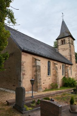 Roth an der Our, Almanya'daki St. Peter Kilisesi - Tapınak Şövalyeleri'nin eski bir kilisesi, dramatik bulutlu gökyüzü altında kısmi yaz dış görünümü