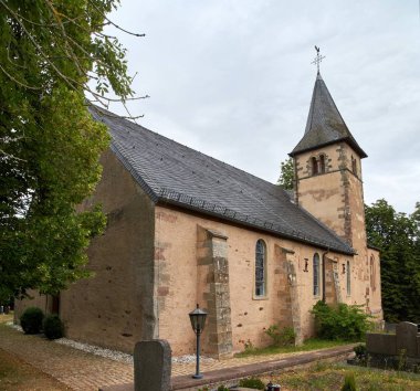 Roth an der Our, Almanya'daki St. Peter Kilisesi - Tapınak Şövalyeleri'nin eski bir kilisesi, dramatik bulutlu gökyüzü altında kısmi yaz dış görünümü