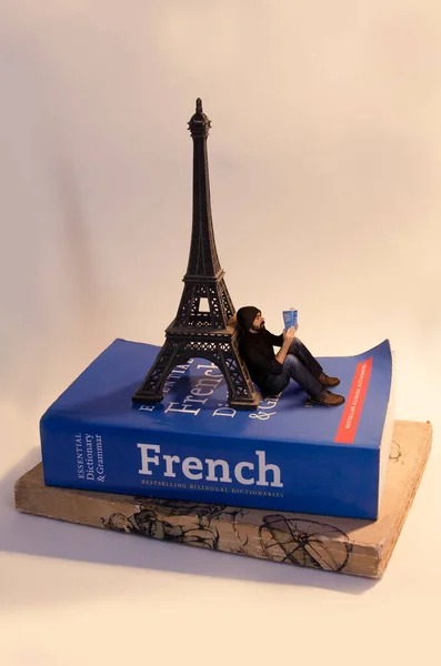 Hombre Miniatura Leyendo Libro Mientras Apoya Una Torre Eiffel Miniatura Fotos de stock