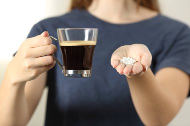 Bir kahve Kupası ve sakarin hap tutan bir kadın elinde kapatın önden görünüm