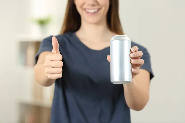 Front view close up of a woman hands holding a soda drink can with thumbs up at home