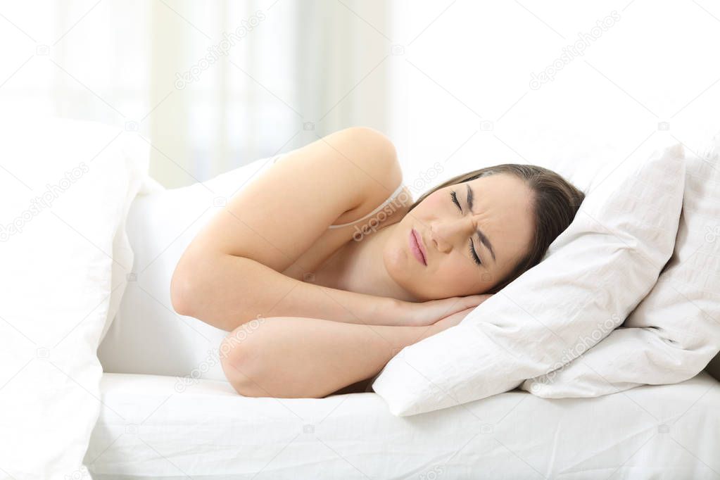 Unhappy woman sleeping on an uncomfortable mattress at home