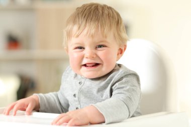 Mutlu bebek sandalyesi üzerinde evde kameraya bakarak gülen