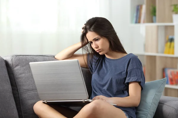 沮丧的青少年阅读在线内容坐在沙发上的客厅在家里 — 图库照片