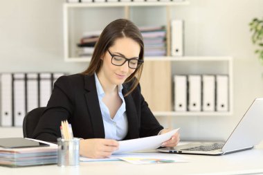 Bir kağıt rapor üstünde a okul sırası okuma gözlük takıyor ofis çalışanı
