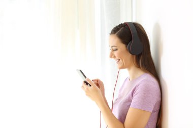 Profil şarkıları bir akıllı telefon evde seçerek müzik dinlemek siyah kulaklık giyen bir mutlu Teen