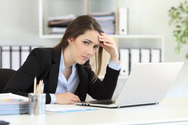 Okul sırası içinde oturan kamera bakarak endişeli ofis çalışanı