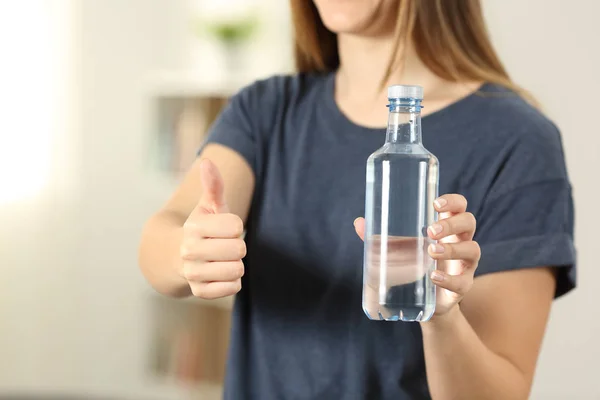 妇女手拿着一瓶水与拇指在家里 — 图库照片