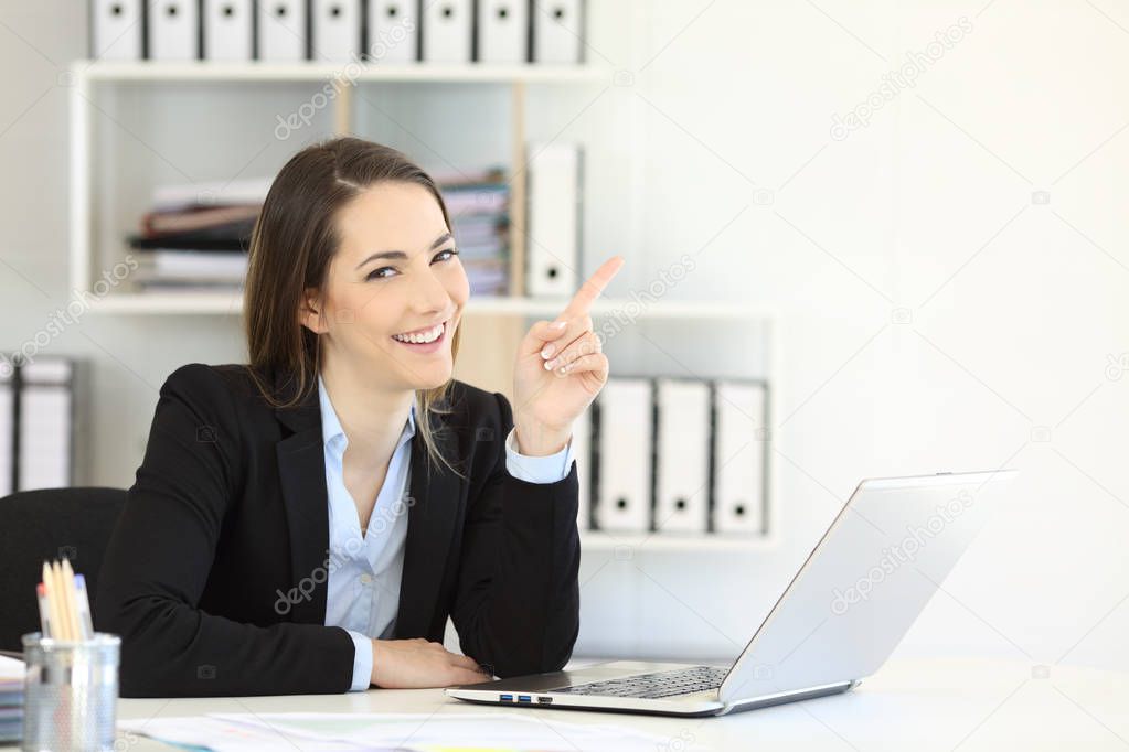Office worker pointing at side at a blank space and looking at camera