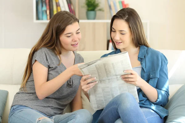 两个朋友在家里的起居室里看报纸新闻坐在沙发上 — 图库照片