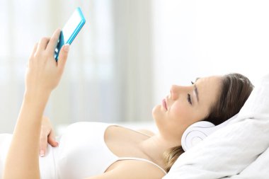 Yan görünümü portresi üzgün bir kız yatakta yatıyordu müzik dinlemek