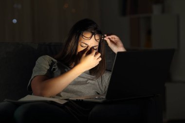 Yorgun kadın gece evde bir dizüstü bilgisayar ile eğitim göz yorgunluğu acı
