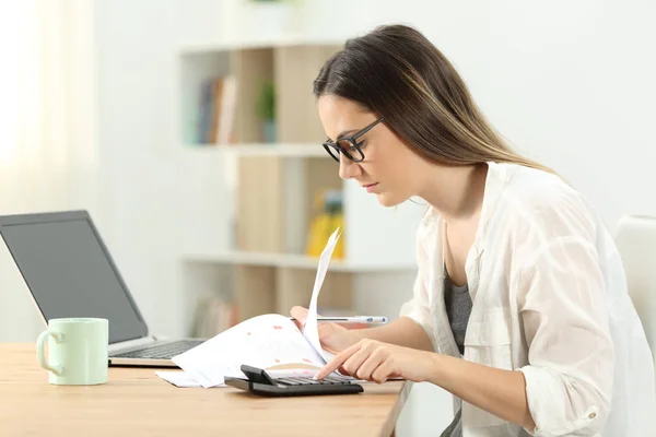 Side view portrait of a concentrated woman doing accounting at home