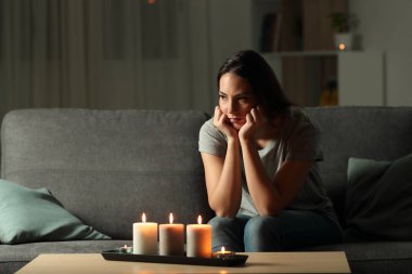 Öfkeli kadın oturma odasında evde bir kanepede oturan gece elektrik kesintisi sırasında sıkıcı