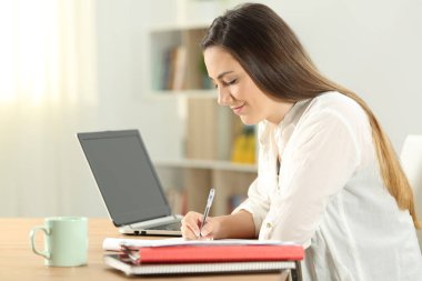 Evde bir defter üzerinde notlar alarak öğrenci profili