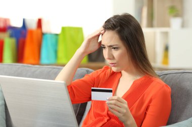 Endişeli müşteri oturma odasında evde bir kanepede oturan kredi kartıyla online satın alma