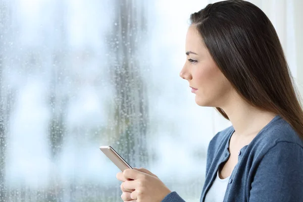 Mulher Triste Segurando Telefone Inteligente Olhando Através Uma Janela Dia — Fotografia de Stock