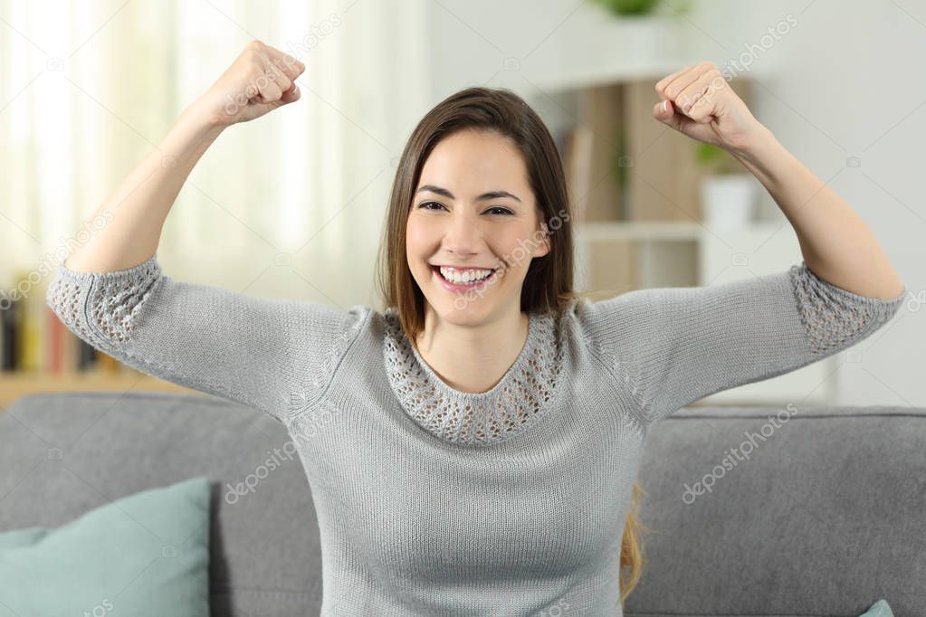 Strong and proud woman gesturling looking at you sitting on a couch in the living room at home