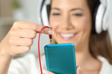 Akıllı telefon için kulaklık jakı konektörü takmayı mutlu kadın el yakın çekim