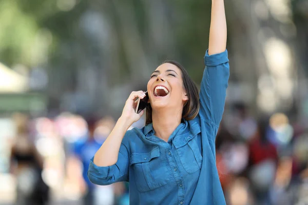 兴奋的妇女收到好消息的电话举起武器在街上 — 图库照片
