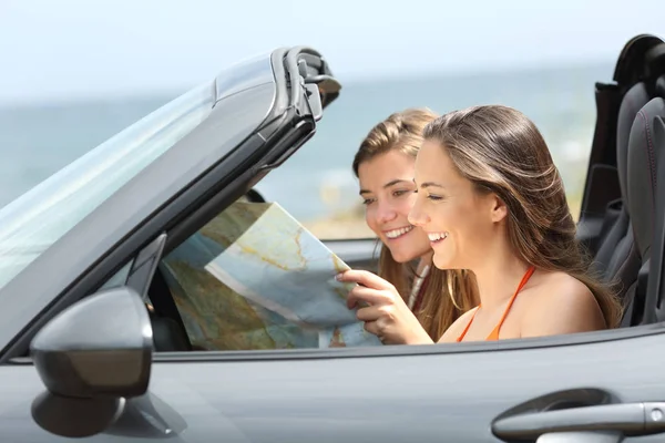 两位游客在一辆可兑换的汽车上阅读地图寻找目的地暑假 — 图库照片