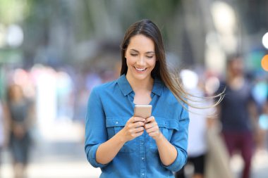 Mutlu bir kadın sokakta bir akıllı telefon mesaj yazma önden görünümü