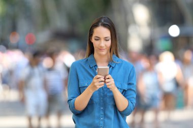 Sokakta yürüyen bir akıllı telefon kullanarak mavi ciddi bir kadında önden görünümü