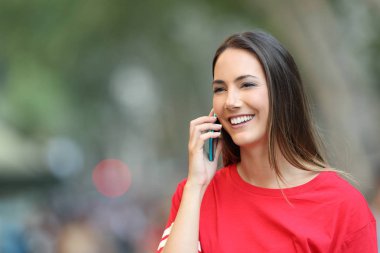 Kırmızı mutlu kız telefonda konuşuyor ve uzağa arıyorsunuz sokakta yürüyor