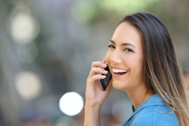 Kameraya bakarak sokakta gülümseyerek telefonu mutlu kız görüşmeler