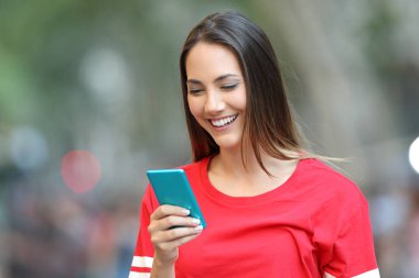 Mutlu bir akıllı telefon sokakta bir iletide Kırmızılı kadın okur