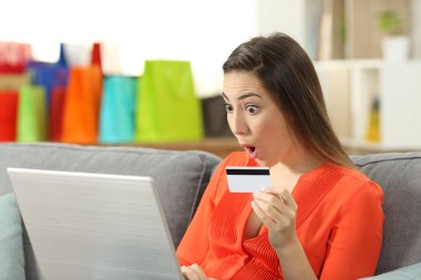 Sürpriz Bayan oturma odasında evde bir kanepede oturan kredi kartıyla ödeme online satın alma