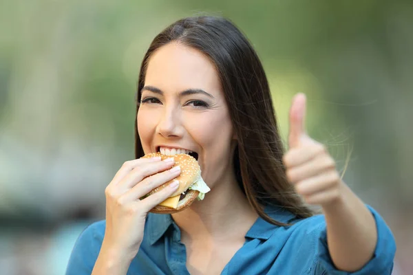 Glückliche Frau Isst Einen Burger Mit Erhobenem Daumen Und Blickt — Stockfoto