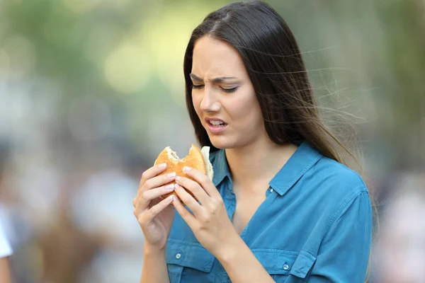 讨厌的女人在街上吃着味道不好的汉堡 — 图库照片