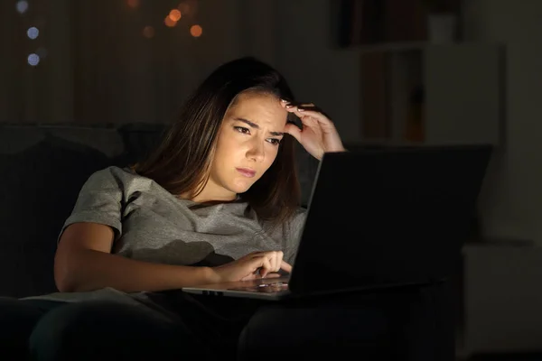 一个担心的女人在晚上在家使用笔记本电脑的肖像 — 图库照片