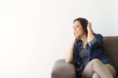 Beyaz bir yalıtılmış duvar tarafına bakarak bir kanepede oturan tek bir kadın portresi