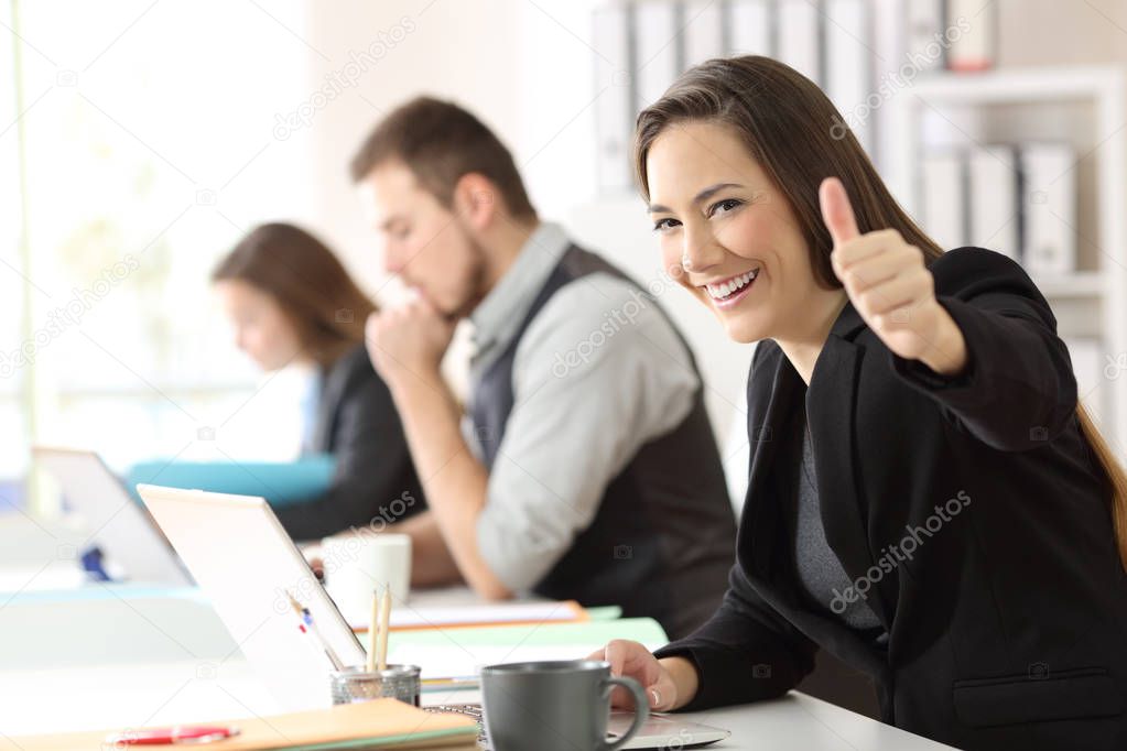 Satisfied business woman with thumbs up at office