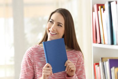 Mutlu kadın yüzüne ve evde duran bir kitap kapağı gösterilen
