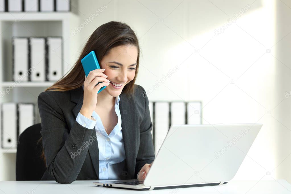 Office worker talking on a phone call and checking data in a laptop