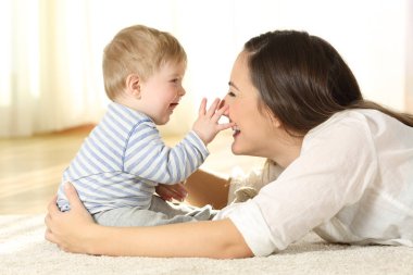 Sevgi dolu anne ve bebek birlikte evde yerdeki bir halı üzerinde oynama
