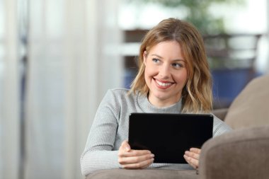 Mutlu bir kadın evde oturma odasında kanepede yatan bir tablet tutan düşünme önden görünümü