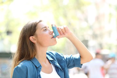 Yan görünümü bir inhaler açık havada sokakta kullanan bir astımlı kadın portresi