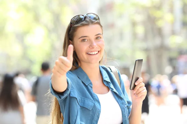 Szczęśliwa Kobieta Uśmiechając Się Trzymając Inteligentny Telefon Kciukiem Góry Ulicy — Zdjęcie stockowe