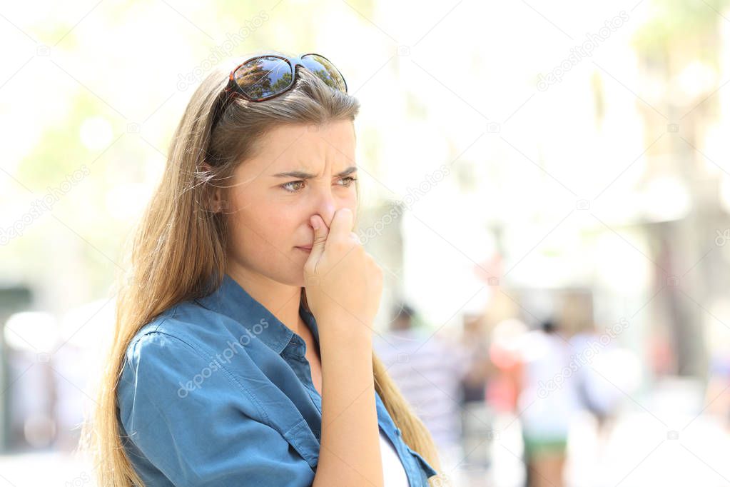 Girl covering her nose due to bad odour in the street