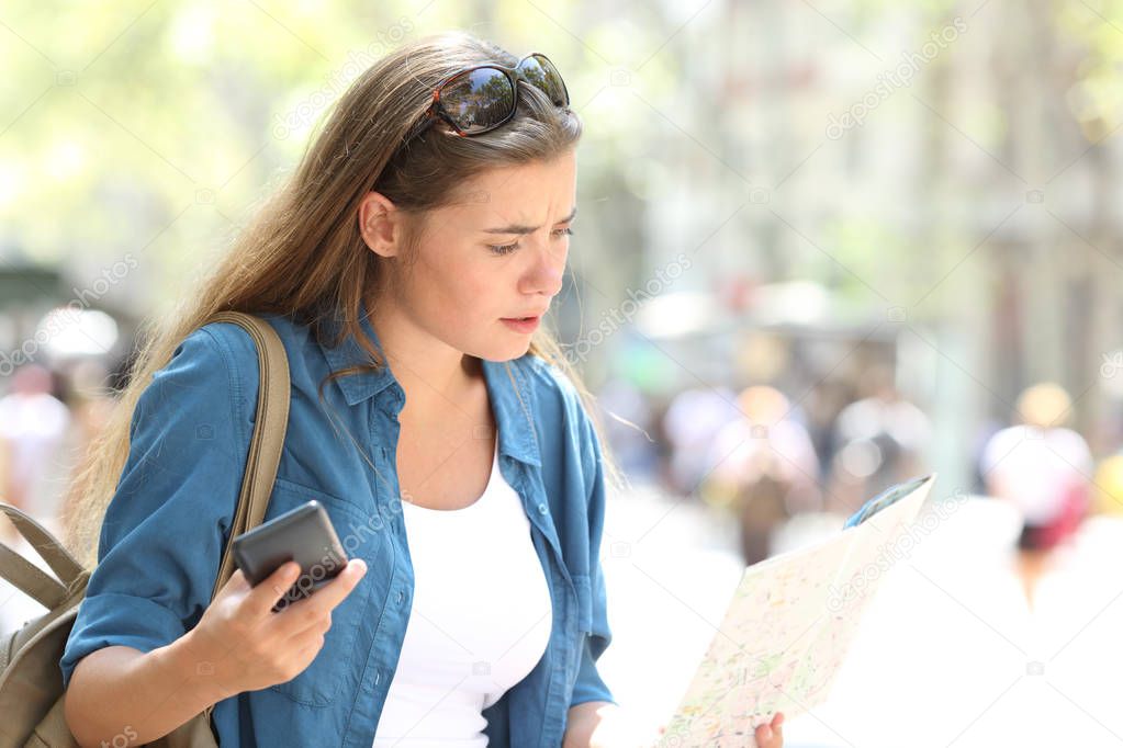 Lost tourist searching direction in a map and a phone in the street