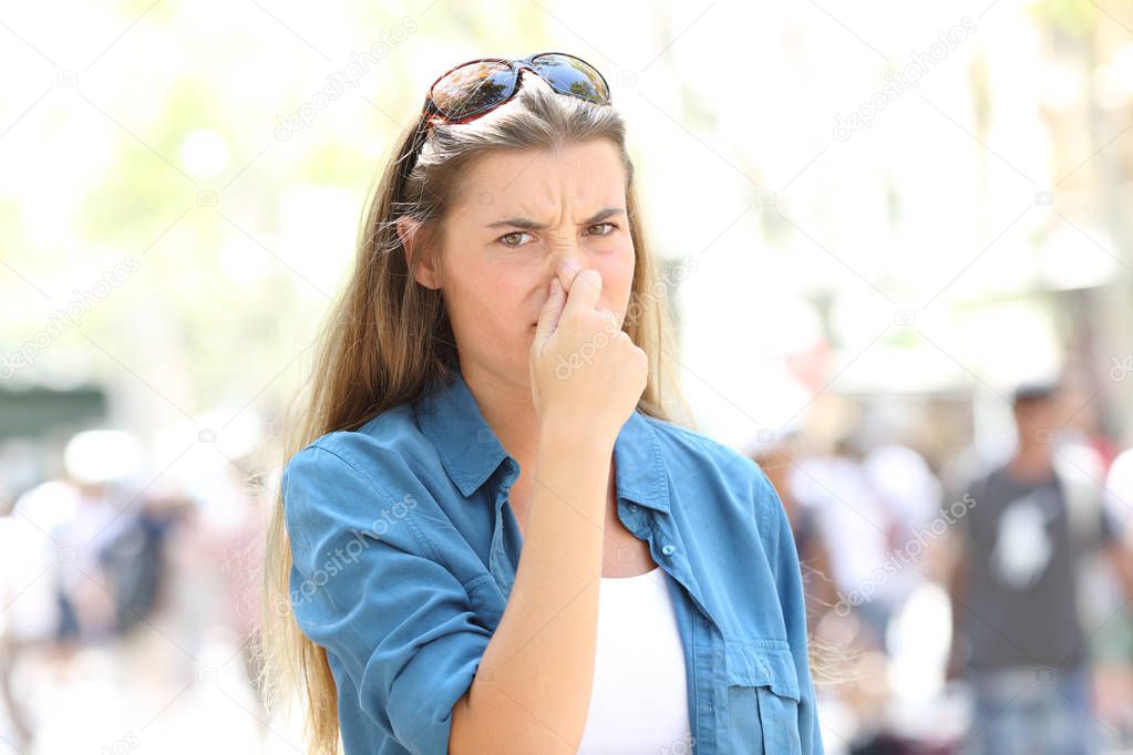 Disgusted woman covering nose in the street of a contaminated city