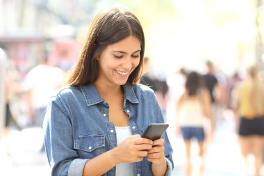 Mutlu genç bir akıllı telefon ayakta sokakta kullanır.