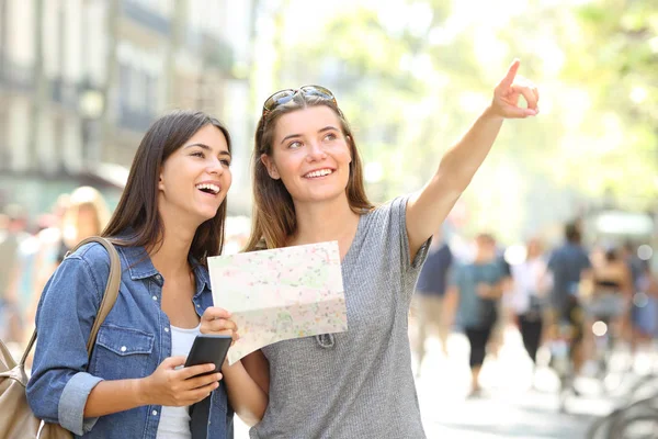 Dois Turistas Felizes Passeando Segurando Mapa Apontando Para Cima Rua — Fotografia de Stock
