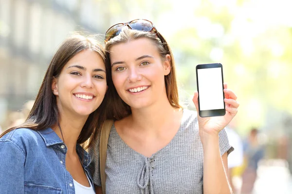 两个快乐的朋友在街上显示一个空白的智能手机屏幕的前视图肖像 — 图库照片