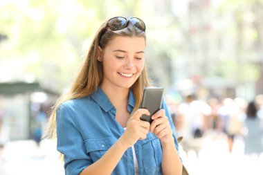 Sokakta bekleyen bir cep telefonu kullanarak gülümseyerek mutlu bir kadın