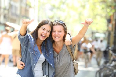 Başparmak ile kameraya ararken yüksek sesle gülerek iki neşeli arkadaşları portresi önden görünüm